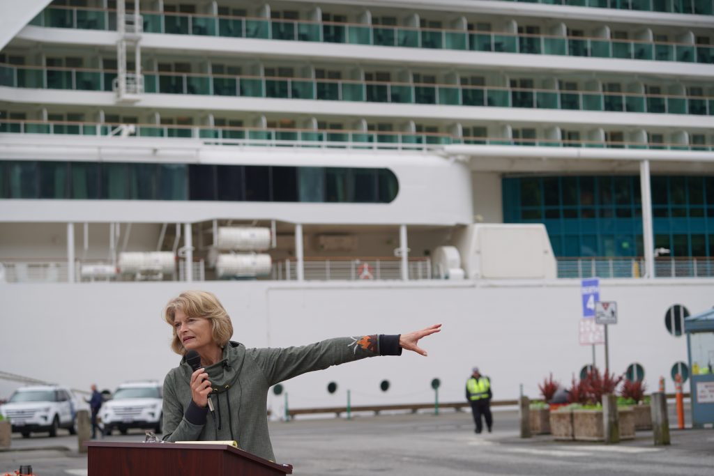 Sen. Lisa Murkowski (R-Alaska) gestures at a cruise ship while speaking from a podium